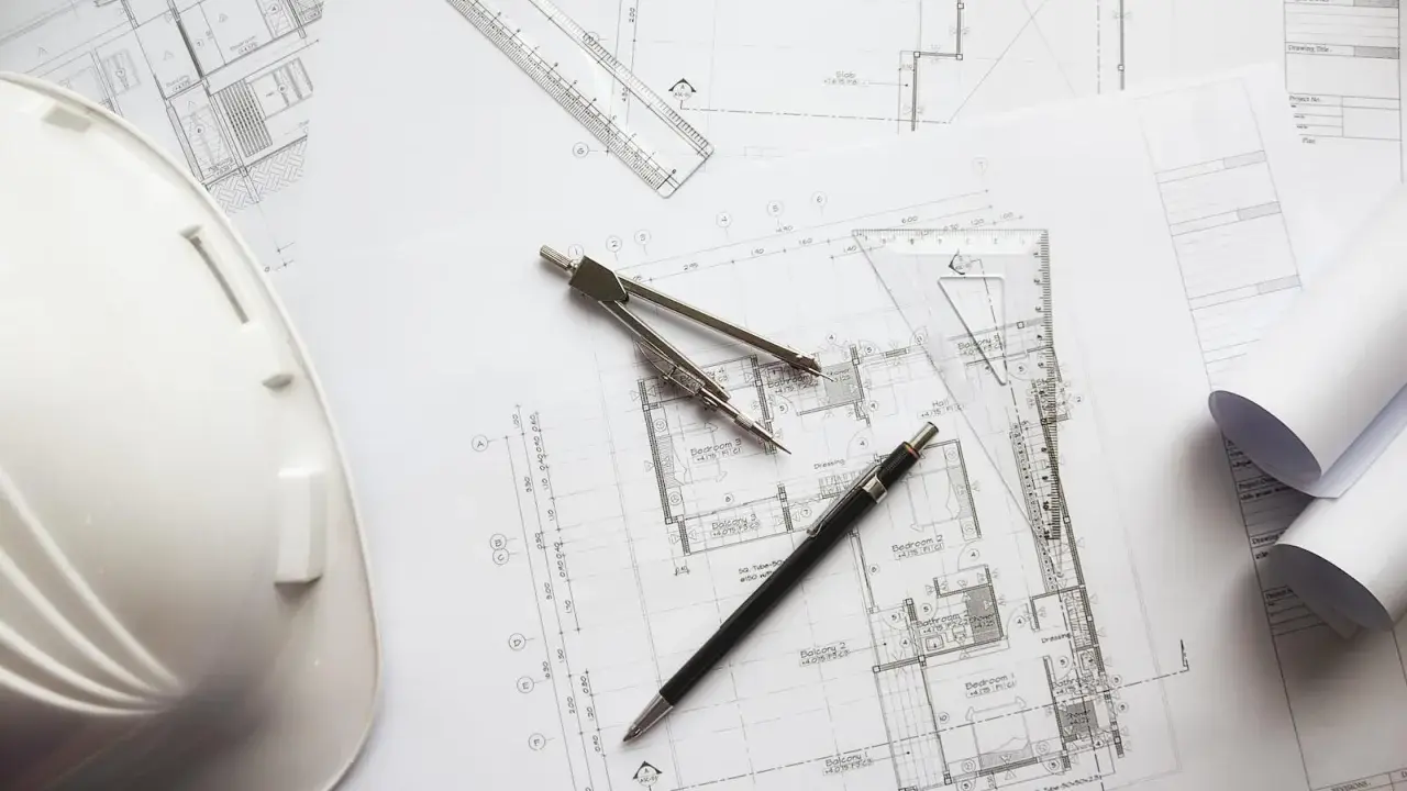Biały kask budowlany, cyrkiel, linijka i długopis leżą na planach architektonicznych. Czy piwnica to kondygnacja?