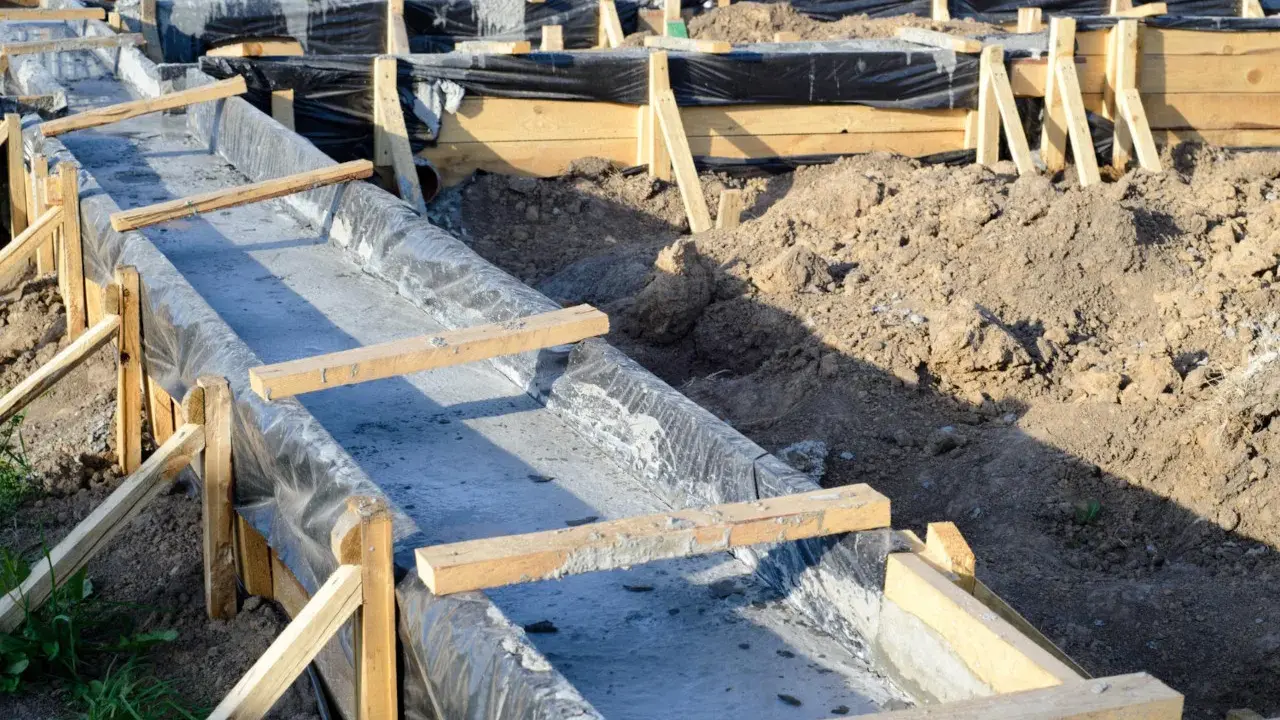 Budowa fundamentów krok po kroku: betonowanie ław fundamentowych w szalunkach z folią.