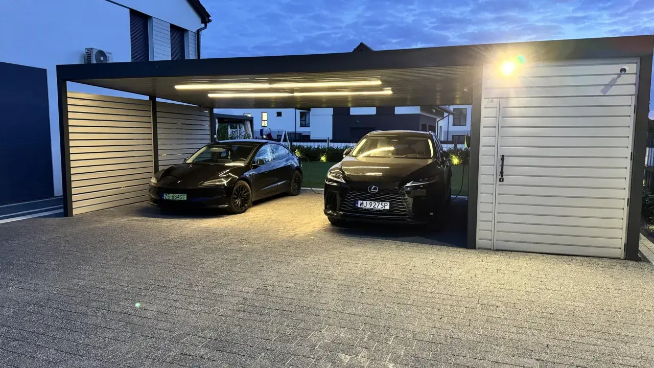 Nowoczesna wiata na 2 samochody projekt. Dwa czarne auta, Tesla i Lexus, stoją pod zadaszeniem z oświetleniem LED.