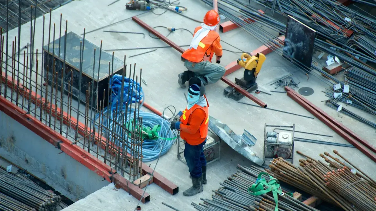 Budowa domu to proces, który wymaga czasu i pracy. Na placu budowy widać robotników i materiały.