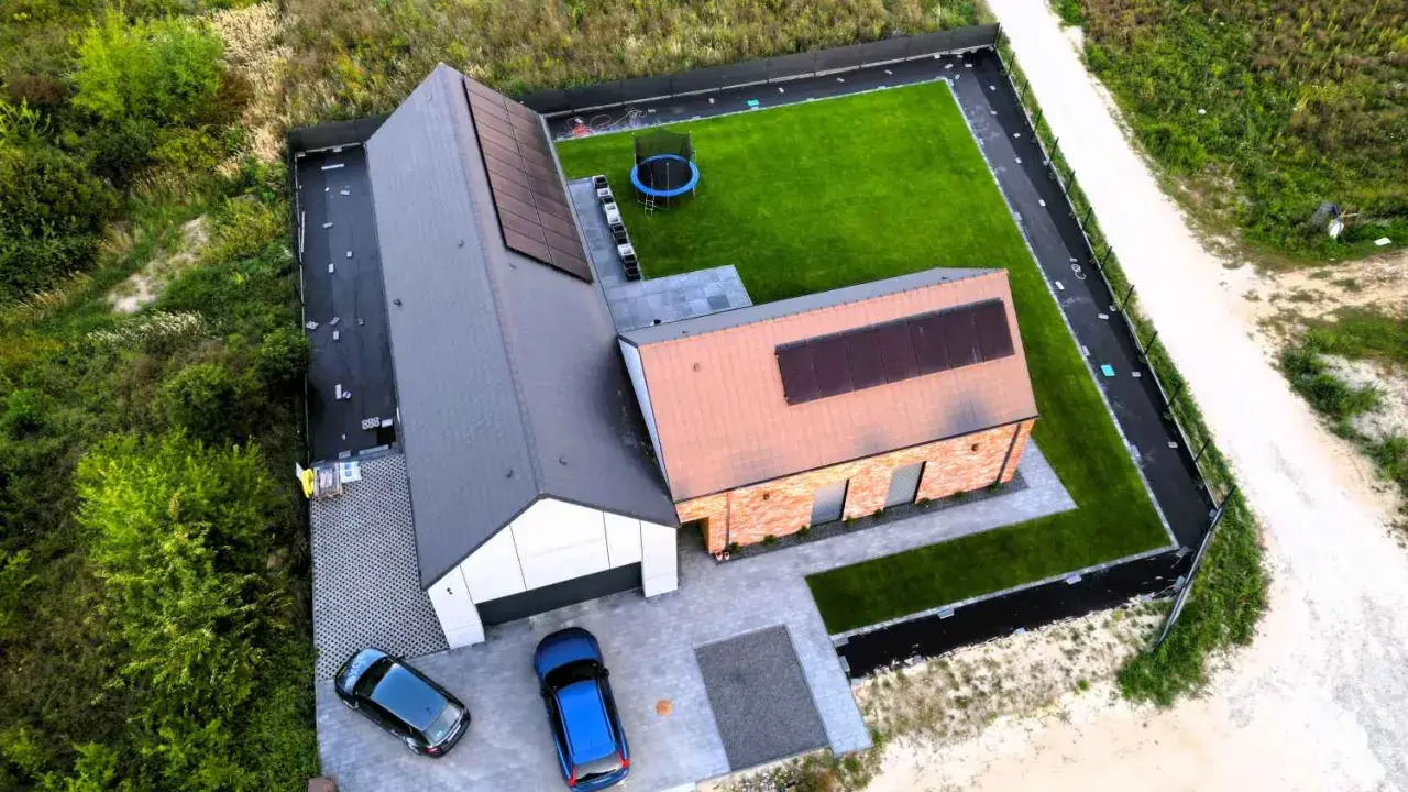 Nowy dom z panelami słonecznymi i zadbanym ogrodem. Dokładna wycena budowy domu pozwoliła na realizację tego projektu.