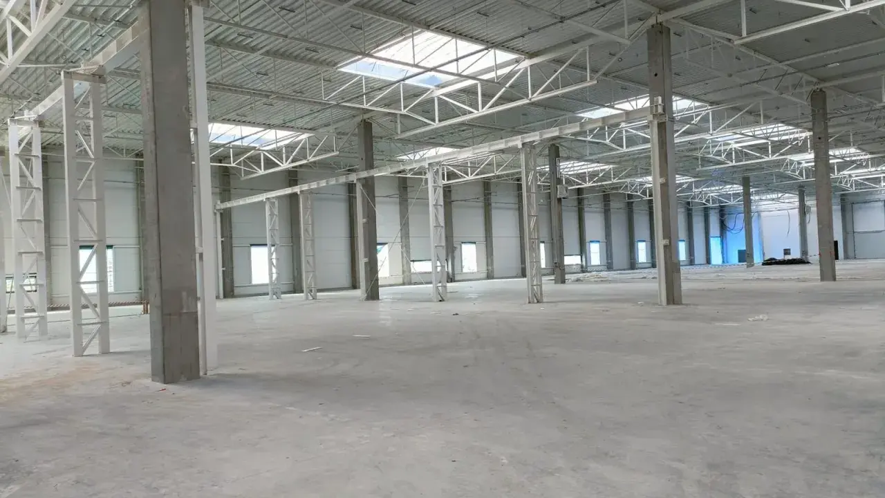 Wnętrze nowej hali magazynowej, betonowe słupy i stalowa konstrukcja dachu. Projekt hali magazynowej w trakcie realizacji.