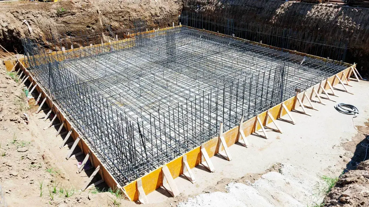 Gotowe zbrojenie ławy fundamentowej 40x60, otoczone drewnianym szalunkiem, czeka na zalanie betonem.