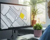 Kobieta analizuje na monitorze mapę działek, która przypomina wypis z rejestru gruntów. Jedna z parceli jest podświetlona na żółto.