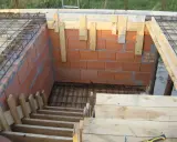Budowa schodów zabiegowych betonowych. Widać zbrojenie, ceglane ściany i drewniane szalunki.