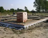 Stan zero budynku: fundamenty z cegły i betonu, stos materiałów budowlanych.