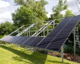 Instalacja PV co to? Panele słoneczne montowane na konstrukcji w ogrodzie, gotowe do produkcji czystej energii.