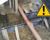 Budowa domu: widoczna rura kanalizacyjna w wykopie, zbrojenie i elementy szalunku.