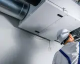 Technik sprawdza wentylację mechaniczną nawiewno-wywiewną. System zapewnia świeże powietrze w budynku.