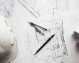 Biały kask budowlany, cyrkiel, linijka i długopis leżą na planach architektonicznych. Czy piwnica to kondygnacja?