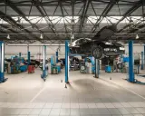 Nowoczesny projekt warsztatu samochodowego. Na podnośnikach stoją auta, mechanicy pracują.