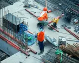 Budowa domu to proces, który wymaga czasu i pracy. Na placu budowy widać robotników i materiały.