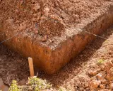 Wyznaczone wykopy pod fundamenty, z widocznymi nićmi wyznaczającymi linie i drewnianym palikiem.