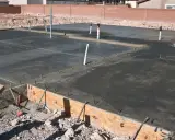 Świeżo wylana płyta betonowa z widocznymi rurami i zbrojeniem. Klasy betonu tabela jest kluczowa dla trwałości tej konstrukcji.