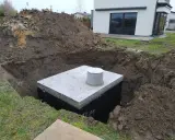 Betonowy zbiornik w wykopie, przygotowany na odpływ z rynny do ziemi.