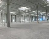 Wnętrze nowej hali magazynowej, betonowe słupy i stalowa konstrukcja dachu. Projekt hali magazynowej w trakcie realizacji.