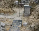Budowa fundamentu z bloczków betonowych, zbrojenie i wózek widłowy w tle.