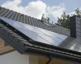 Nowoczesny dach z paneli fotowoltaicznych, szary komin i dachówka. Dom gotowy na zieloną energię.