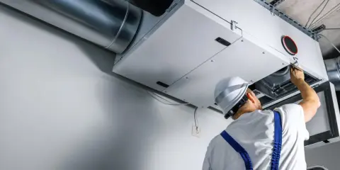 Technik sprawdza wentylację mechaniczną nawiewno-wywiewną. System zapewnia świeże powietrze w budynku.