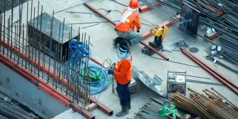 Budowa domu to proces, który wymaga czasu i pracy. Na placu budowy widać robotników i materiały.