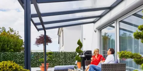 Para relaksu na tarasie na dachu. Para siedzi na kanapie pod zadaszeniem, popijając wino.