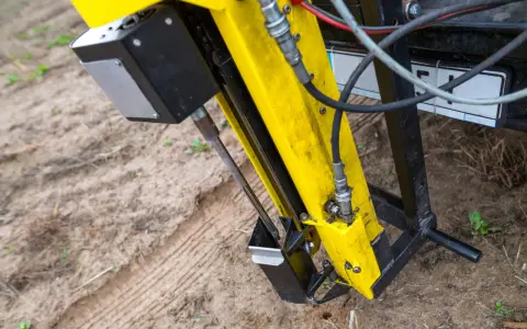 Żółta maszyna do badań geotechnicznych gruntu w akcji. Wiertło zagłębia się w ziemię, zbierając próbki do analizy.