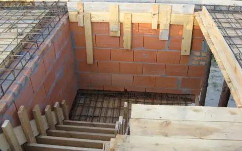 Budowa schodów zabiegowych betonowych. Widać zbrojenie, ceglane ściany i drewniane szalunki.