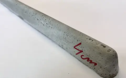 Szary, betonowy element, jeden z dystansów pod zbrojenie, z oznaczeniem "4 cm" na czerwono.