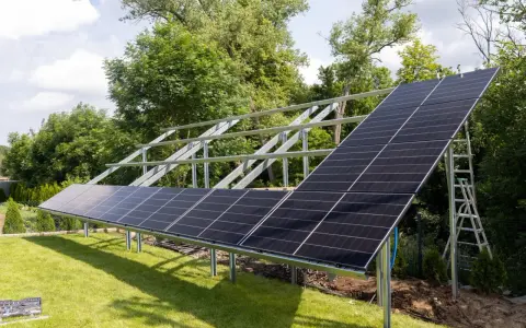 Instalacja PV co to? Panele słoneczne montowane na konstrukcji w ogrodzie, gotowe do produkcji czystej energii.