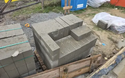 Rozpoczęto murowanie z bloczków betonowych. Układane są pierwsze warstwy, tworząc zarys przyszłej konstrukcji.