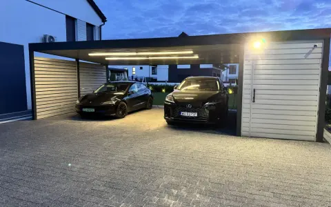 Nowoczesna wiata na 2 samochody projekt. Dwa czarne auta, Tesla i Lexus, stoją pod zadaszeniem z oświetleniem LED.