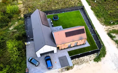 Nowy dom z panelami słonecznymi i zadbanym ogrodem. Dokładna wycena budowy domu pozwoliła na realizację tego projektu.