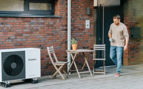Mężczyzna wychodzi z domu obok pompy ciepła Vaillant. Jaka pompa ciepła zapewni komfort i oszczędność?