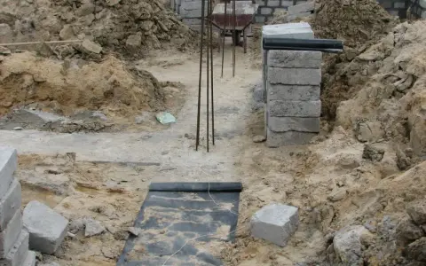 Budowa fundamentu z bloczków betonowych, zbrojenie i wózek widłowy w tle.