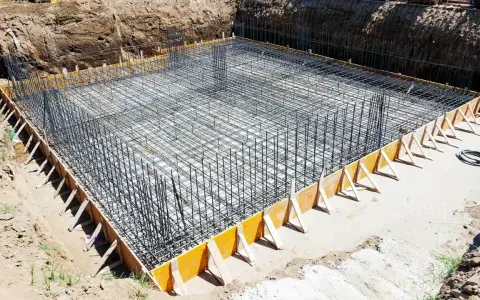 Gotowe zbrojenie ławy fundamentowej 40x60, otoczone drewnianym szalunkiem, czeka na zalanie betonem.
