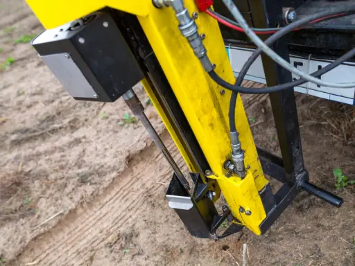 Żółta maszyna do badań geotechnicznych gruntu w akcji. Wiertło zagłębia się w ziemię, zbierając próbki do analizy.