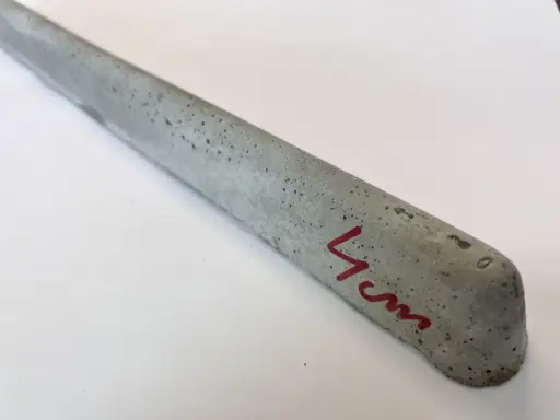 Szary, betonowy element, jeden z dystansów pod zbrojenie, z oznaczeniem "4 cm" na czerwono.