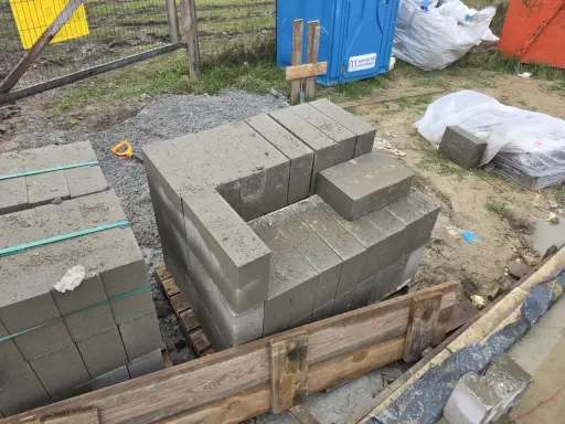 Rozpoczęto murowanie z bloczków betonowych. Układane są pierwsze warstwy, tworząc zarys przyszłej konstrukcji.
