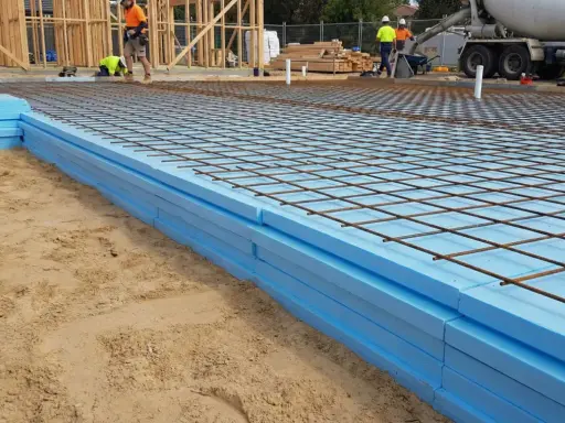 Styrodur pod płytę fundamentową ułożony na piasku, z siatką zbrojeniową gotową do zalania betonem.