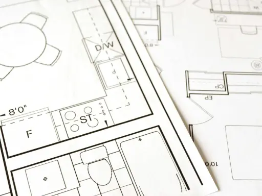 Plany architektoniczne z kuchnią, łazienką i stołem. Kluczowe etapy: warunki zabudowy a pozwolenie na budowę.