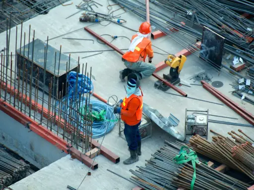 Budowa domu to proces, który wymaga czasu i pracy. Na placu budowy widać robotników i materiały.