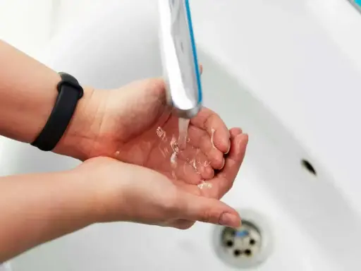 Dłonie pod bieżącą wodą z kranu. Zastanawiasz się, jak zwiększyć ciśnienie wody? Sprawdź nasze porady!