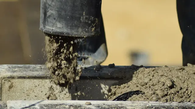Mieszanka styrobetonowa wypływa z czarnej rury, pokazując, jak zrobić styrobeton.