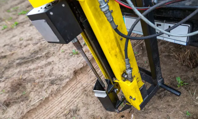 Żółta maszyna do badań geotechnicznych gruntu w akcji. Wiertło zagłębia się w ziemię, zbierając próbki do analizy.