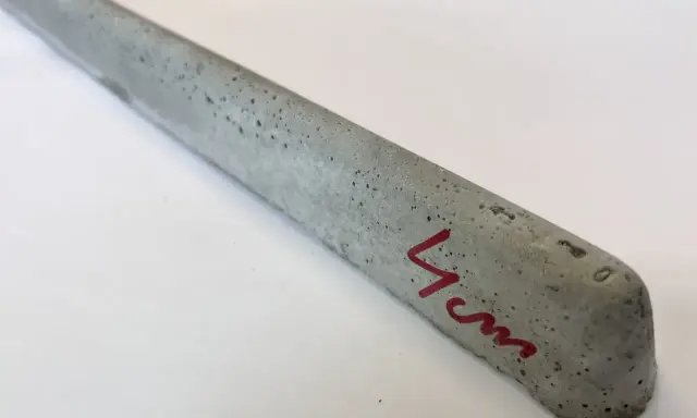 Szary, betonowy element, jeden z dystansów pod zbrojenie, z oznaczeniem "4 cm" na czerwono.