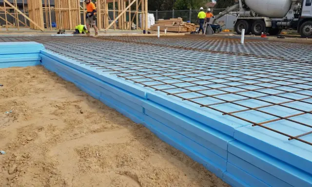 Styrodur pod płytę fundamentową ułożony na piasku, z siatką zbrojeniową gotową do zalania betonem.