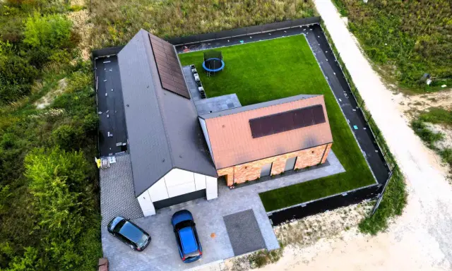 Nowy dom z panelami słonecznymi i zadbanym ogrodem. Dokładna wycena budowy domu pozwoliła na realizację tego projektu.