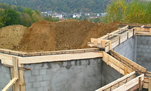 Fundamenty domu w budowie, zbrojenie i szalunki czekają na beton. Ważne jest pozwolenie na budowę, by wszystko szło zgodnie z planem.