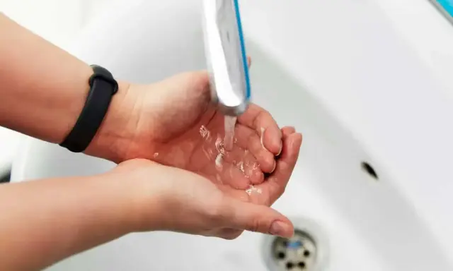 Dłonie pod bieżącą wodą z kranu. Zastanawiasz się, jak zwiększyć ciśnienie wody? Sprawdź nasze porady!