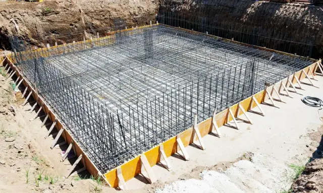 Gotowe zbrojenie ławy fundamentowej 40x60, otoczone drewnianym szalunkiem, czeka na zalanie betonem.